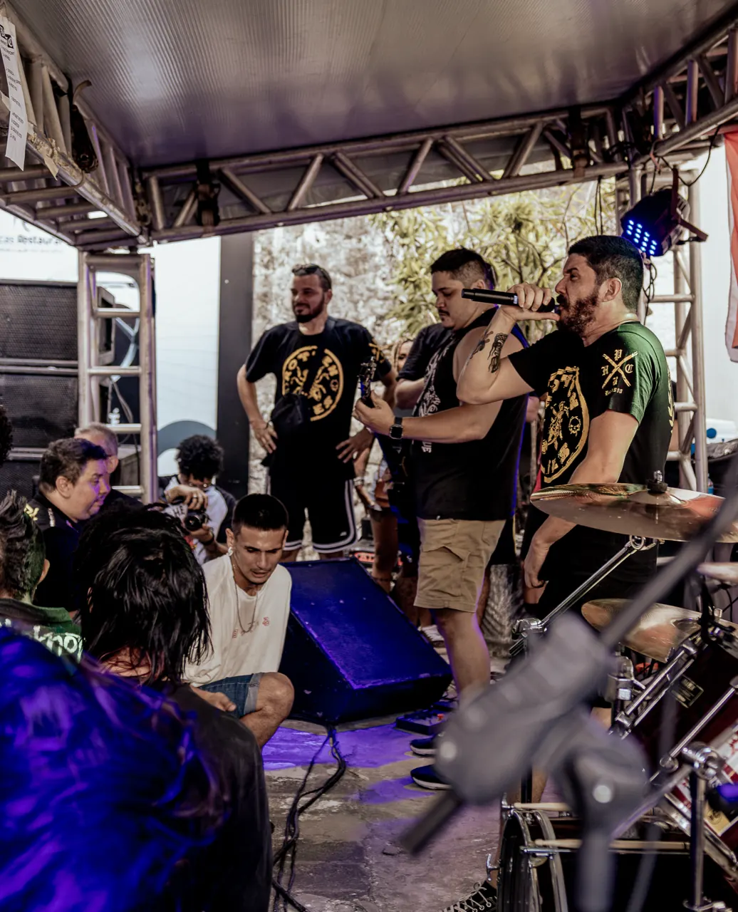 A banda no palco coberto do show de rua, com o público colado na frente.
