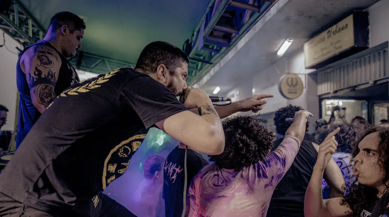 O vocalista se inclina sobre o público, que estende as mãos para cantar junto.