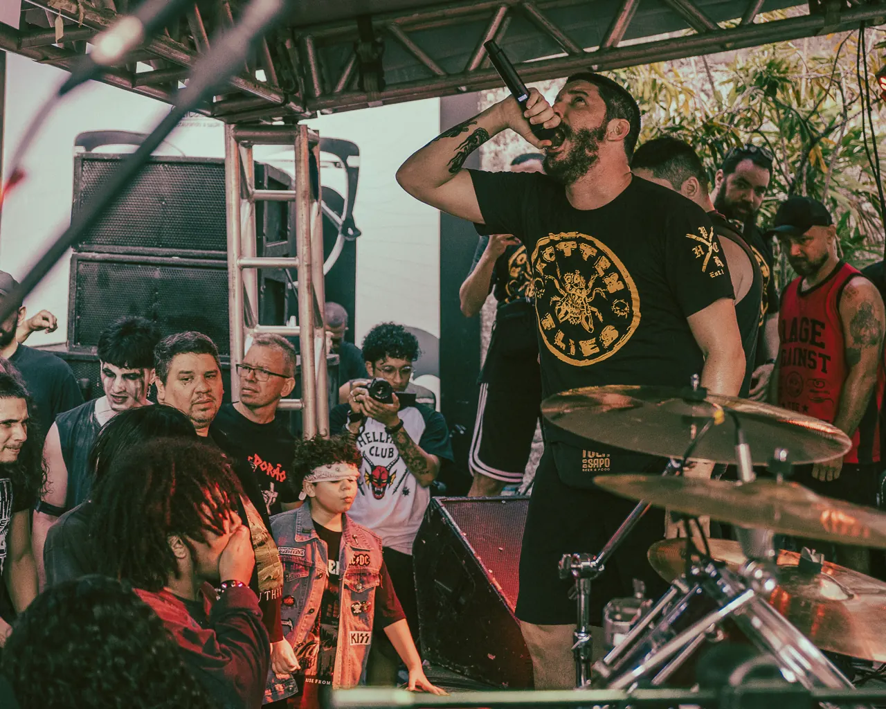 Vocalista ergue o microfone enquanto a plateia canta na frente do palco.